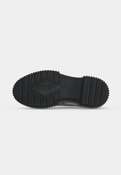 Semelle de chaussure en caoutchouc noir avec un motif antidérapant texturé et le mot ADIEV embossé en forme de losange au centre.