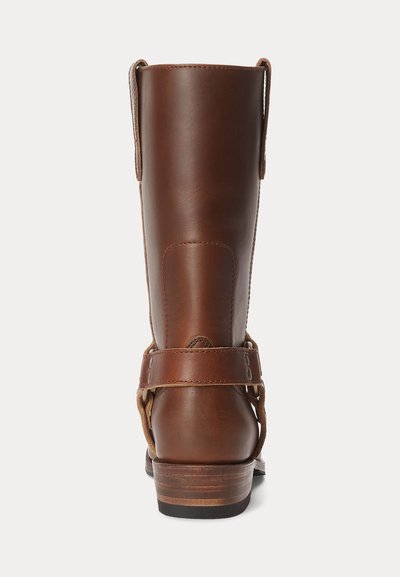 Pruun nahast sääre keskmise kõrgusega saabas rakmerihma ja tõmblukkudega, puidust kontsaga, vaadates tagant valgel taustal.