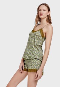 Set di pigiama verde a fantasia composto da un top senza maniche con bordi a scallop e pantaloni shorts abbinati, entrambi con design floreali e paisley.