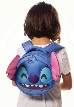 Mochila azul redonda con una cara de dibujos animados que tiene ojos grandes, dientes afilados y orejas rosas. Correas ajustables azules. Material suave.