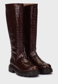 Botas de rodilla burdeos con textura de piel de cocodrilo, con puntera redonda y suela de goma negra gruesa. Cremallera lateral para facilitar el uso.