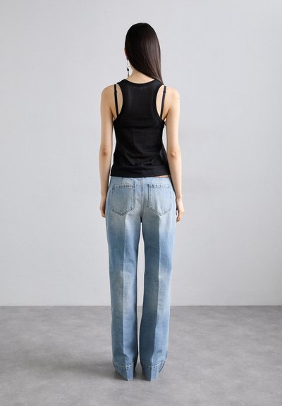 Zwarte, aansluitende tanktop met dunne bandjes, gecombineerd met lichtblauwe, hoge taille wijde broek met een vervaagde afwerking en traditionele achterzakken.