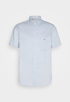 Šviesiai mėlyna trumpomis rankovėmis marškiniai su mygtukų apykakle, turintis kairėje krūtinės pusėje kišenę ir mažą logotipo detalę. Pagaminta iš lygaus audinio.