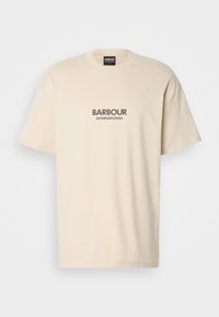 Kremowa bawełniana koszulka z krótkim rękawem i okrągłym dekoltem, z napisem "BARBOUR INTERNATIONAL" w ciemnoszarym kolorze na środku. Gładka tekstura.