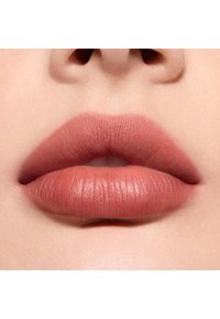 Rouge à lèvres mat nude sur des lèvres pulpeuses, mettant en valeur une texture lisse avec un éclat subtil, dans une teinte rose-marron neutre.