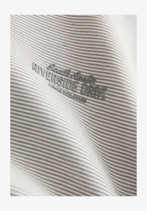 Hallitusseente ja valge triibuline kangas sujuva tekstuuriga, millel on reljeefne tekst "South Austin Riverside Drive" ja "Lamar Boulevard."