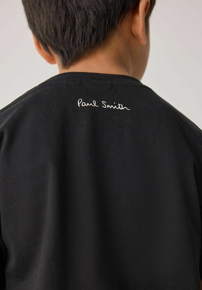 Svart t-shirt i bomull med rund hals, med vit snirklig "Paul Smith" broderi på baksidan. Slät textur.