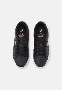 Baskets en cuir noir avec semelles blanches, dotées d'une finition texturée, de lacets noirs et d'un logo rose subtil sur la languette et le côté.