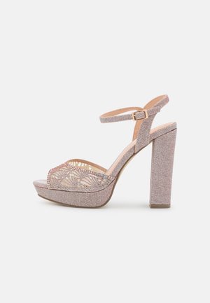 Lyserøde højhælede sandaler med en tekstureret overdel, åben tå, og en ankelrem med spænde. Pyntet med dekorative detaljer.