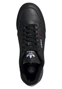 Melna vegāna ādas apava ar perfozētu purngalu, plakaniem šņorēm un baltu Adidas logo uz mēles. Iezīmēts ar sarkanu akcentu sānos.