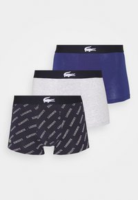 Tres pares de calzoncillos tipo boxers: azul marino oscuro con patrón de logotipos blancos, gris claro y azul oscuro sólido, con una cinturilla negra que lleva un logotipo.