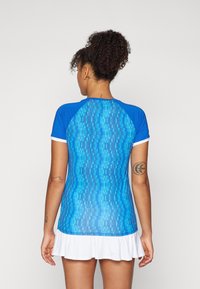 Blue athletic top with a textured geometric pattern, short sleeves, and a white flared hem. Smooth, stretchable fabric.