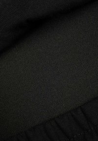 Czarna teksturowana tkanina z prążkowanym wzorem na górze oraz marszczoną sekcją na dole, co sugeruje, że jest to materiał rozciągliwy.