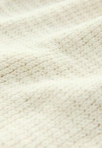 Texturiertes cremefarbenes Gewebe mit einem gewebten Muster, weicher Optik und leichtem Fall, geeignet für Bekleidung oder Heimtextilien.