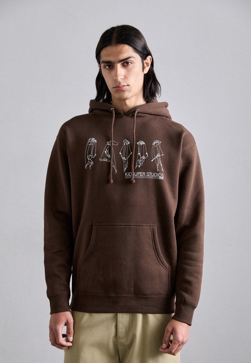 Brown cotton hoodie featuring a front pocket and a white graphic print with hand illustrations. Adjustable drawstring hood. Plain texture.