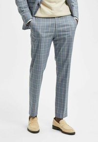 Ljusblå rutig byxa med skräddarsydd passform och en slät yta. Kombinerad med beige loafers för att framhäva en smart-casual stil.