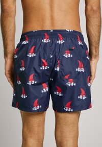 Mornarska kopalna kratka hlača iz lahkega materiala, s ponavljajočim se vzorcem rdečih klobukov in belih obrazov, z elastičnim pasom in stranskim žepom.