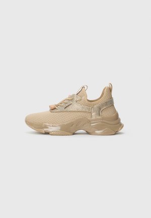 Beige nettverks-sneaker med tykk gummisåle, slip-on design, elastiske bungee-snører, og glatte teksturerte overflater på hælen og sidene.