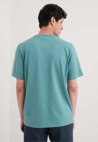Teal rundhalsad t-shirt med korta ärmar, tillverkad av mjukt tyg, med en slät yta och en enkel design. Inga synliga mönster eller detaljer.