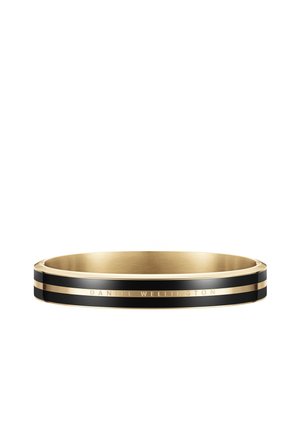 Gold and black bangle bracelet with glossy finish, featuring a narrow black stripe and engraved "DANIEL WELLINGTON" accent.