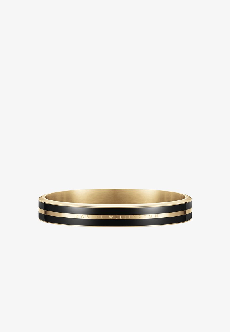 Kullatud ja musta värvi bangle-käevõru läikiva viimistlusega, millel on kitsas must triip ja graveeritud "DANIEL WELLINGTON" aksent.