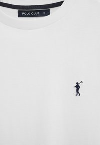 Maglietta bianca con etichetta Polo Club nera e piccolo giocatore di polo nero ricamato a mano che tiene un mazza sul petto.