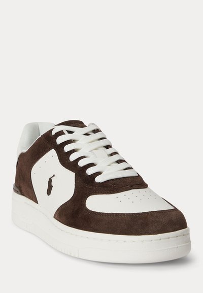 Κοντό sneaker με λευκό δέρμα και σκούρα καφέ πάνελ από σουέντ, λευκά κορδόνια, διάτρητη μύτη και μικρό σκούρο λογότυπο αλόγου στο πλάι.
