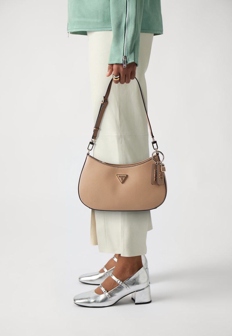 Borsa a mano in pelle beige con forma semicircolare, bordi neri e logo a triangolo. Dotata di una tracolla abbinata, con dettagli di portachiavi.