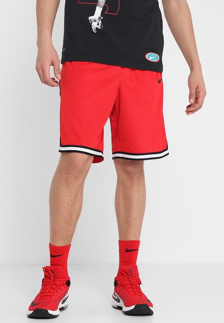 Červené sportovní šortky s černo-bílým lemováním, vyrobené z materiálu odvádějícího vlhkost. Kombinovány s červenými ponožkami a červeno-černými teniskami.