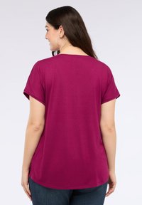 Fuchsia T-shirt med korte ærmer og en afslappet pasform, med en rund kant og opfoldede manchetter, lavet af et blødt, glat stof.