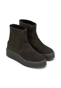 Bottines en daim noir avec semelles nervurées, présentant des coutures minimales et une silhouette lisse. Conception sans zip pour un enfilage facile.