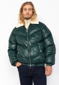 Green puffer jacket with a shiny finish, featuring a cream fleece collar, zip closure, side pockets, and elasticated cuffs and hem.