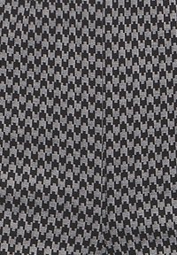Close-up of fabric with black and gray houndstooth pattern featuring a central seam running vertically.