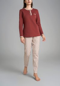Maglietta a maniche lunghe color marrone bordeaux con bottoni e pantaloni da pyjama crema a scacchi, caratterizzati da un design aderente e una texture morbida.