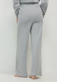 Graue Baumwoll-Loungehosen mit entspanntem Schnitt, ausgestattet mit einem elastischen Bund und weit geschnittenen Beinen. Weiche Textur und keine sichtbaren Muster.