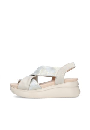 Sandalo con zeppa beige con cinturini incrociati in metallo e pelle, suola imbottita, punta aperta e cinturino posteriore con chiusura a gancio.