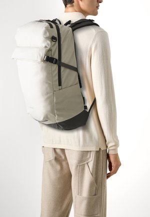 Gray and black backpack with a top flap, featuring adjustable straps, a zippered front pocket, and smooth textured fabric.