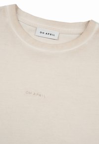 Κρεμ T-shirt με στρογγυλή λαιμόκοψη, με μικρό λογότυπο κειμένου "OH APRIL" στο στήθος και ετικέτα στο εσωτερικό του γιακά που ταιριάζει.
