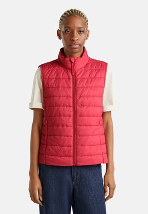 Rode gewatteerde vest met hoge kraag en ritssluiting, met een gestroomlijnd ontwerp en een gewatteerde textuur, gedragen over een T-shirt met korte mouwen.