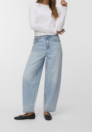 Jeans a gamba larga di un blu chiaro in denim, con vita alta, caratterizzati da un design a cinque tasche e cuciture a contrasto, abbinati a ballerine nere.