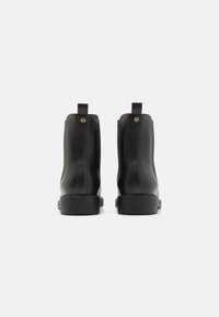 Botine din piele neagră, până la gleznă, cu un finisaj neted, având un toc mic și pătrat, panouri elastice laterale și câte un tab pe spate.