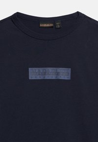 Μπλούζα μπλε ναυτικού με στρογγυλή λαιμόκοψη και ορθογώνιο σκούρο μπλε λογότυπο στ η μέση του στήθους που αναγράφει "Napapijri geographic".