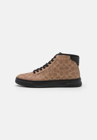 Tan hoge sneakers met een patroon op de bovenkant, zwarte rubberen zool, ronde neus en zwarte veters. Heeft logo-opdruk op de achterkant.