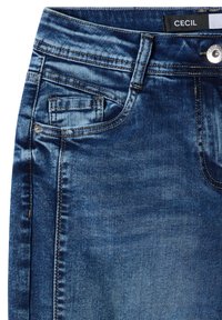 Jean en denim bleu montrant une poche avant, une petite poche monnaie, une boucle de ceinture, un bouton métallique et une étiquette noire avec le nom de la marque "CEcil".