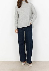 Pull à col roulé surdimensionné gris clair associé à un jean large taille haute bleu foncé et des escarpins argentés à bouts pointus ornés.