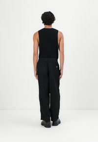 Black sleeveless top and loose-fit black pants, featuring a drawstring waist, back pockets, and textured material.