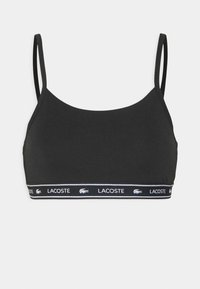 Svart sports-BH med tynne stropper, laget av glatt stoff. Har en elastisk band med merkevarenavnet "LACOSTE" i hvitt og logo.