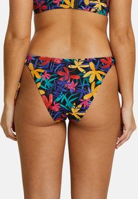 Bas de bikini avec un motif floral vibrant rouge, jaune et vert sur fond noir, avec une coupe haute et une texture lisse.