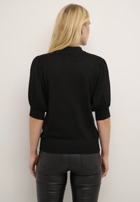 Sort kortærmet strikket sweater med en let glitrende tekstur, puffede ærmer og en tætsiddende silhuet. Glat bagdesign, minimale accenter.