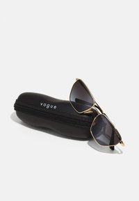 Črn prozoren etui z zadrgo, označen kot "vogue"; sončna očala z zlatim tonom, temno sivo steklo, angularna oblika in tanek kovinski okvir.